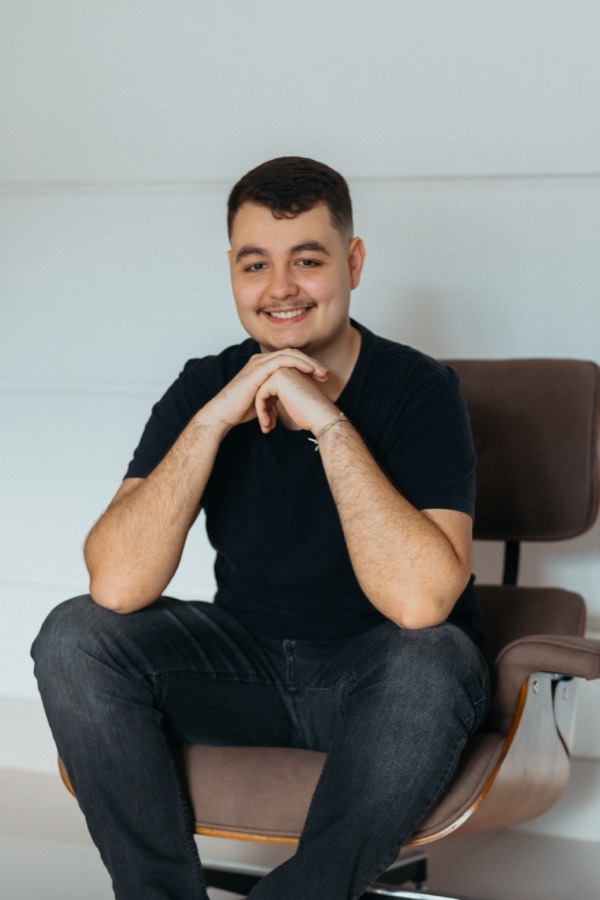 Lucas Couto, seated, smiling, wearing a dark t-shirt